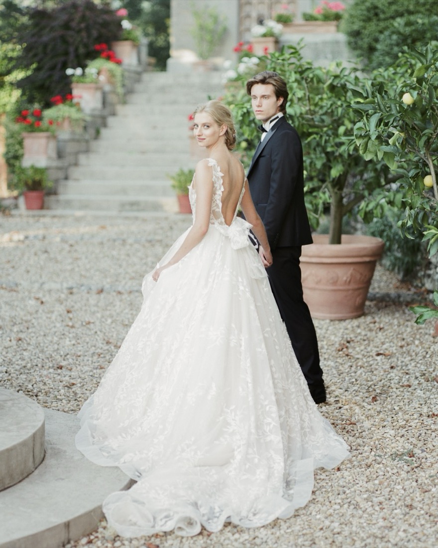 Bride and groom on a stone staircase lined with potted flowers and lemon trees
