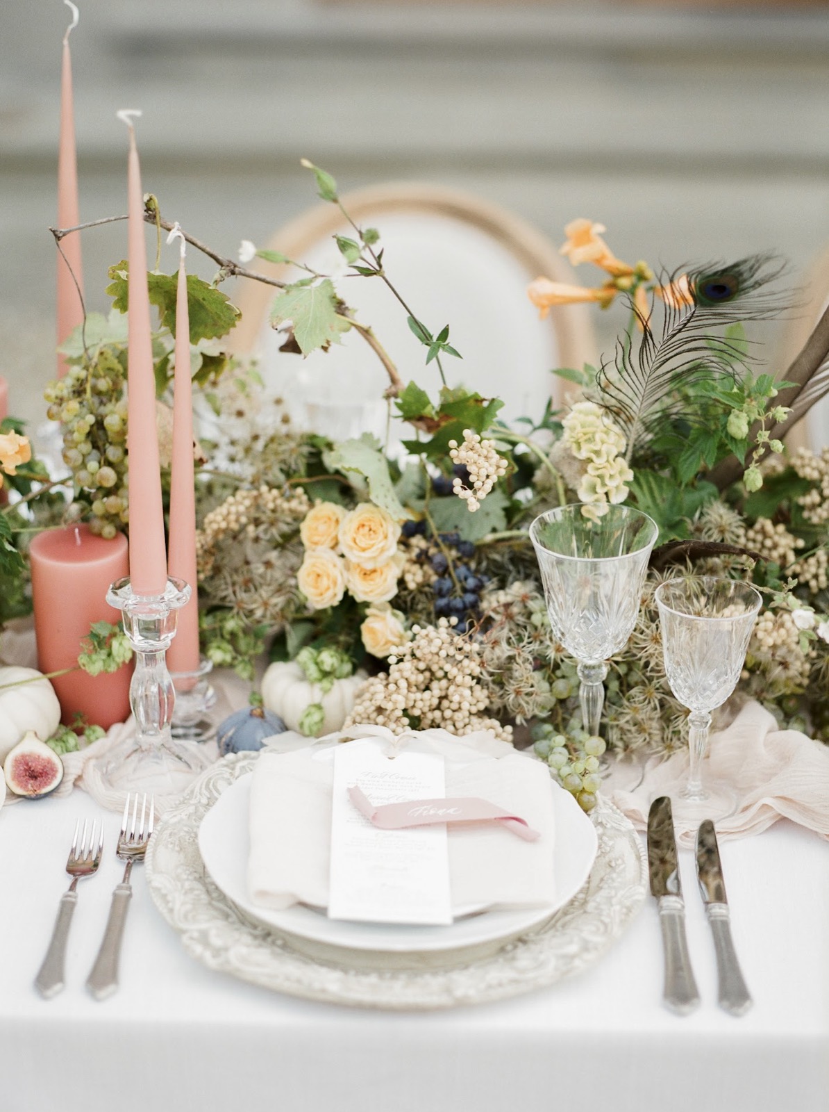 Romantic reception table with taper candles, garden roses, grapes and a peacock feather in an autumnal palette
