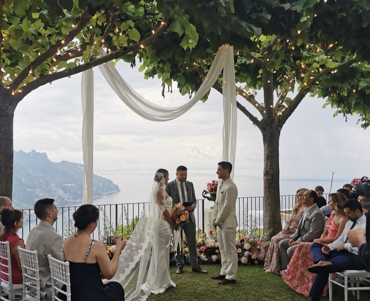 Bride, groom and celebrant beneath a fairy-lit canopy overlooking the Amalfi coastline