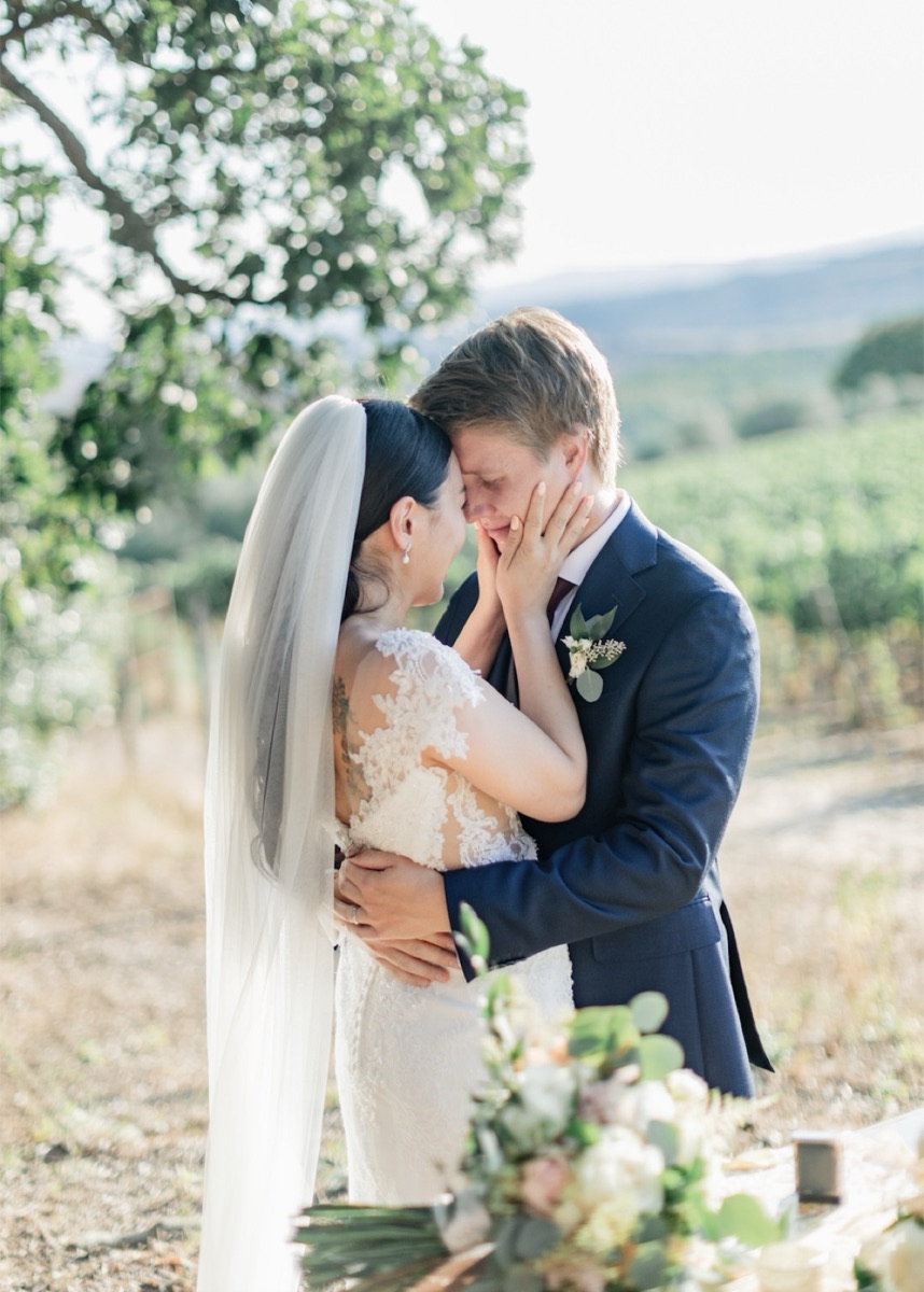 Lisa and Jarkko embracing forehead to forehead beside a Tuscan vineyard