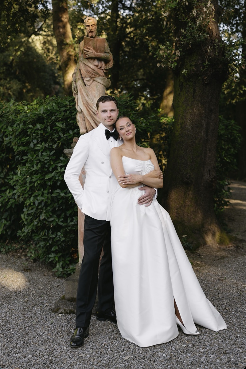 Freja and Daniel embracing in front of a garden statue beneath the trees