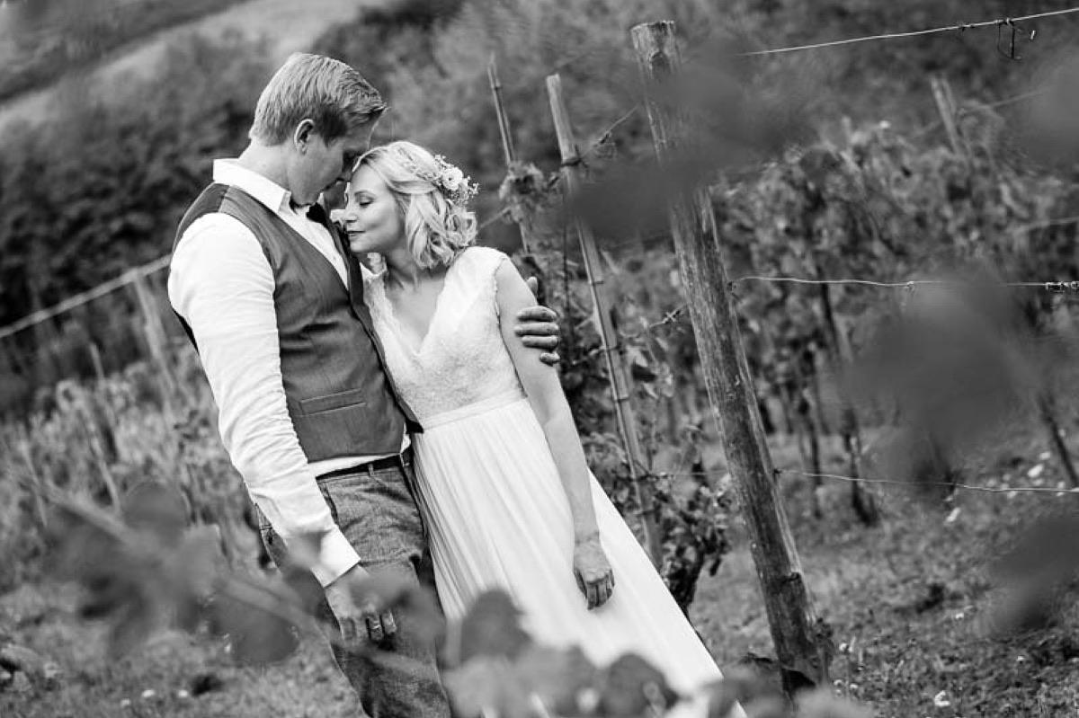 Black and white portrait of bride and groom embracing among vineyard rows in Tuscany
